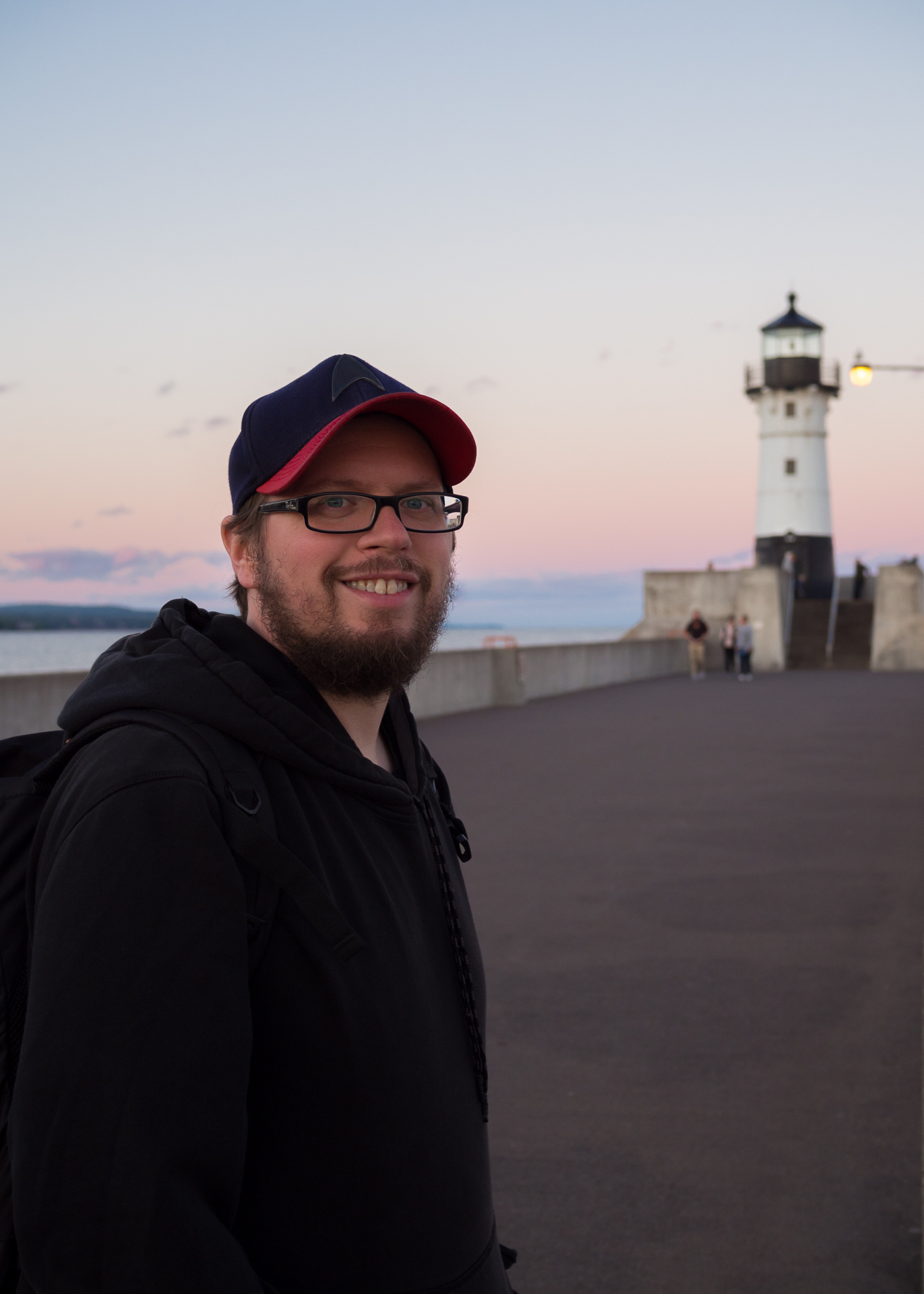 Dan Voltz standing in front of Duluth pier lighthouse at sunset